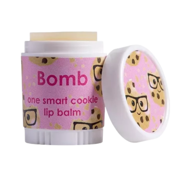 Lip balm container labeled "Bomb" featuring a playful design with cookie characters wearing glasses on a pink background, with the text "one smart cookie lip balm" displayed prominently on the front. The cap is slightly open, revealing the balm inside.